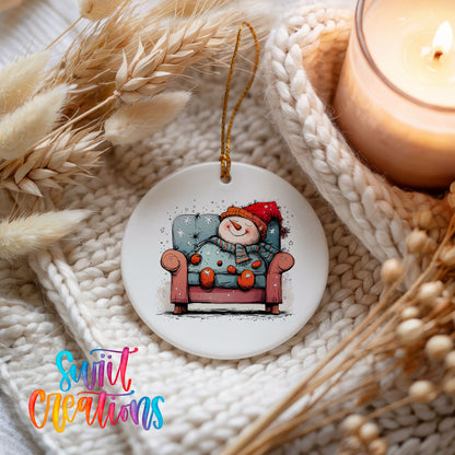 Santa Resting in a Holiday Armchair Christmas ornament styled beside a candle and cozy knit blanket