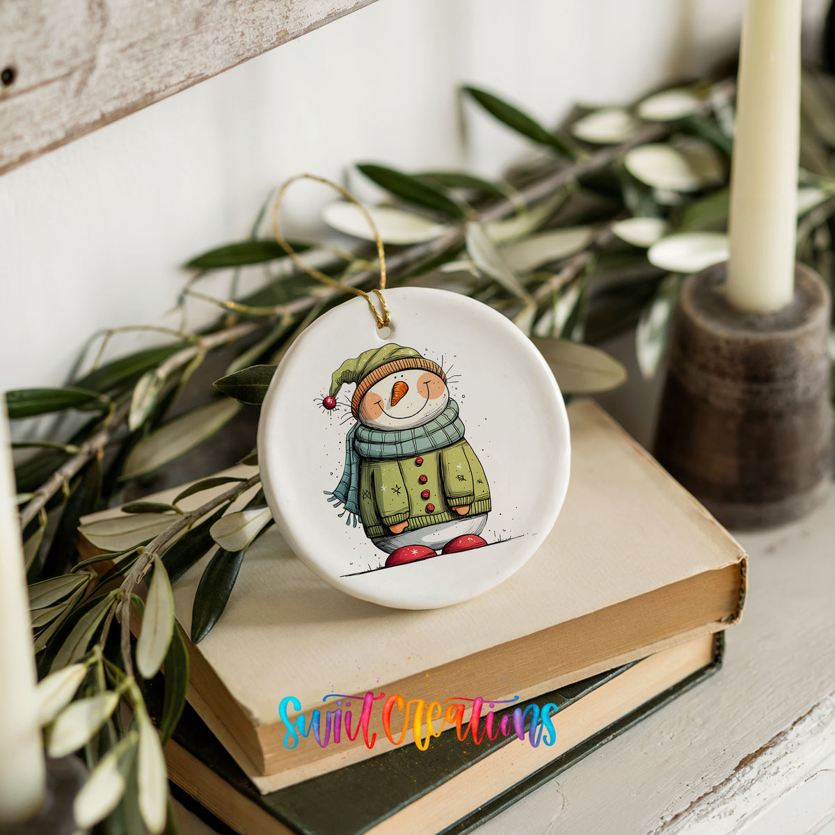 Snowman in Green Winter Coat Christmas ornament styled on books with holiday greenery