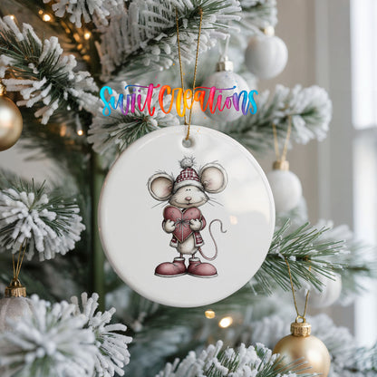 pink mouse holding a heart ceramic Christmas ornament hanging on a frosted Christmas tree