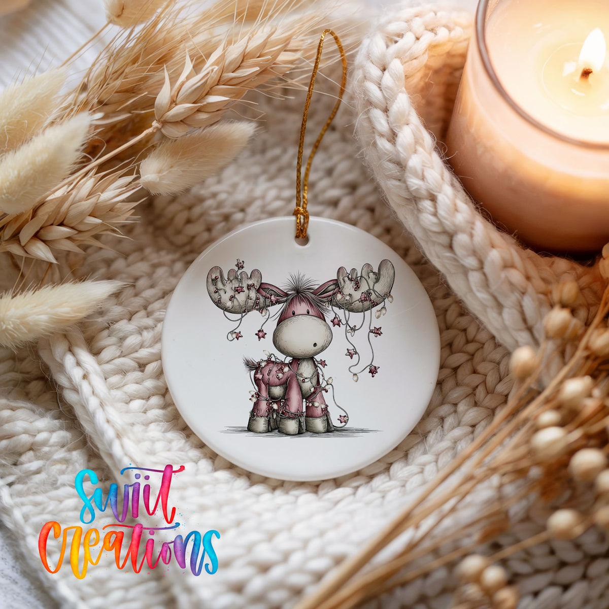 pink reindeer with hanging ornaments ceramic Christmas ornament styled on a cozy knit blanket