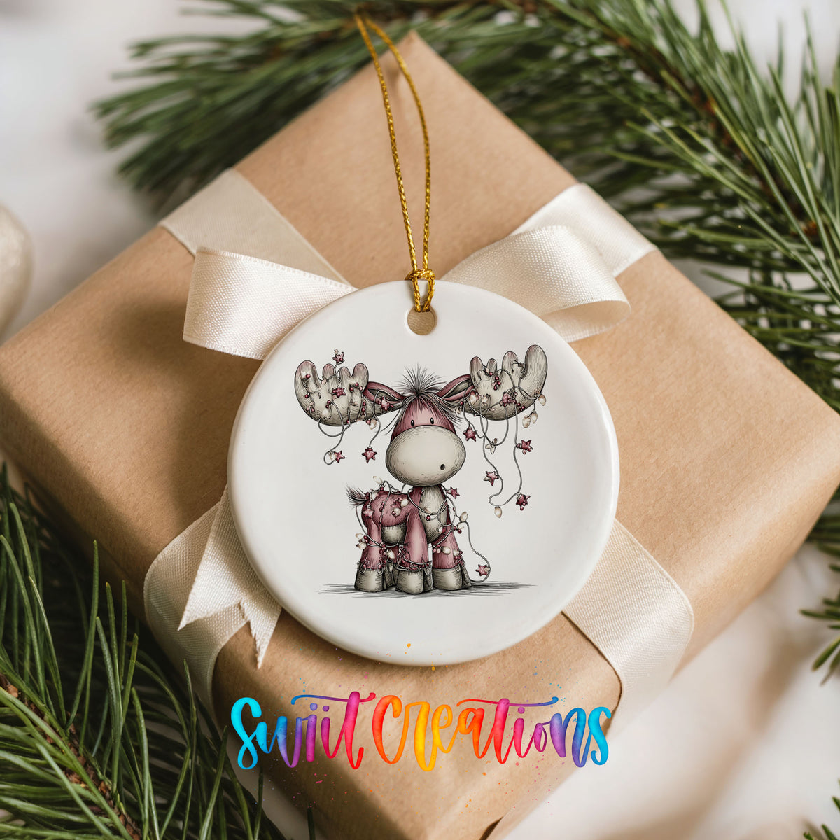 pink reindeer with hanging ornaments ceramic Christmas ornament displayed on a wrapped Christmas gift