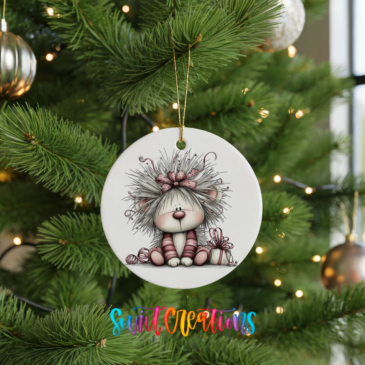 white and pink kitten in a floral winter headpiece ceramic Christmas ornament hanging on a lit Christmas tree