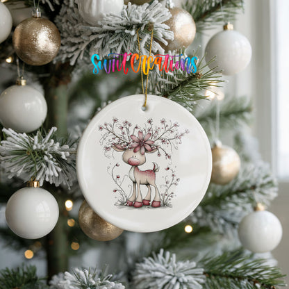 pink reindeer with snowy floral antlers ceramic Christmas ornament hanging on a frosted tree with ornaments