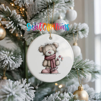 teddy bear in a pink scarf holding a candy cane ceramic Christmas ornament hanging on a frosted Christmas tree