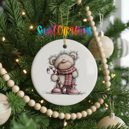 teddy bear holding a candy cane in winter clothes ceramic Christmas ornament hanging on a green Christmas tree