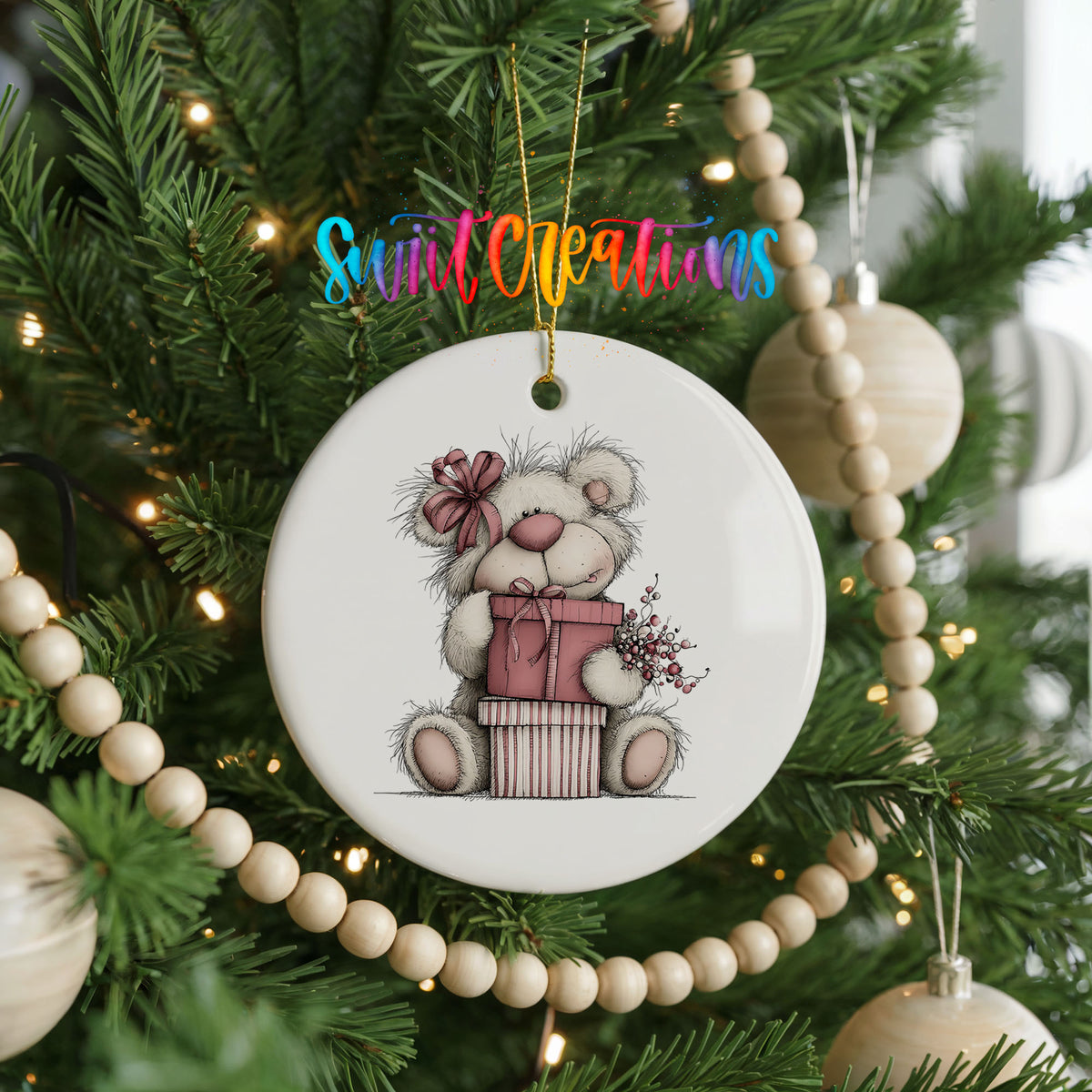 teddy bear sitting on a wrapped Christmas gift ceramic Christmas ornament hanging on a green Christmas tree