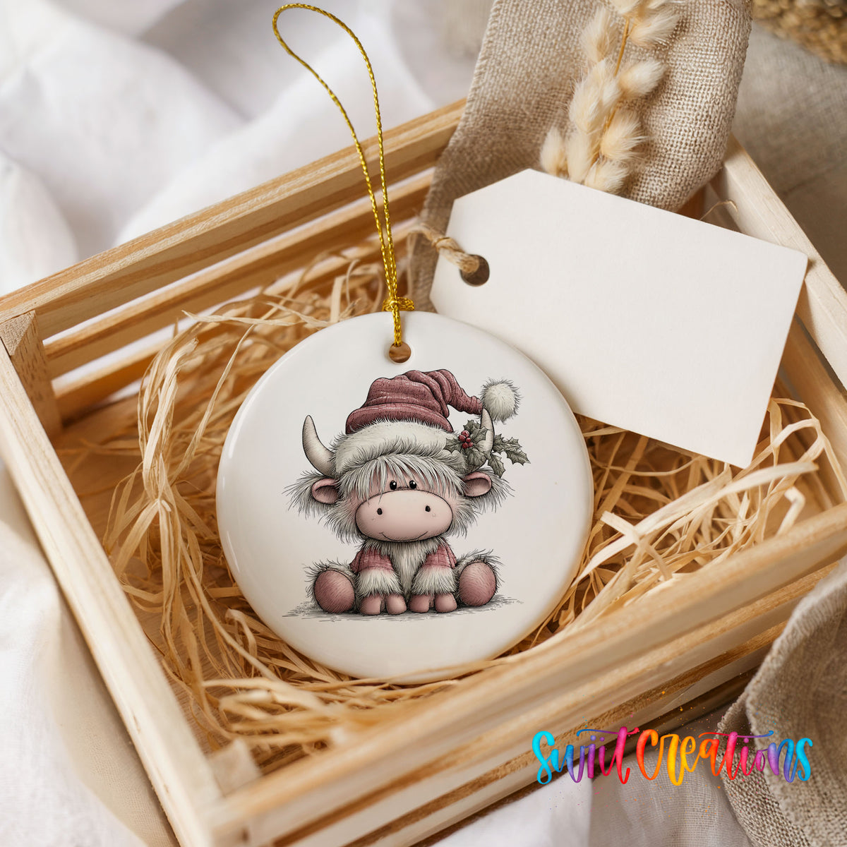 Highland cow in a pink Santa hat ceramic Christmas ornament displayed in a wooden gift crate