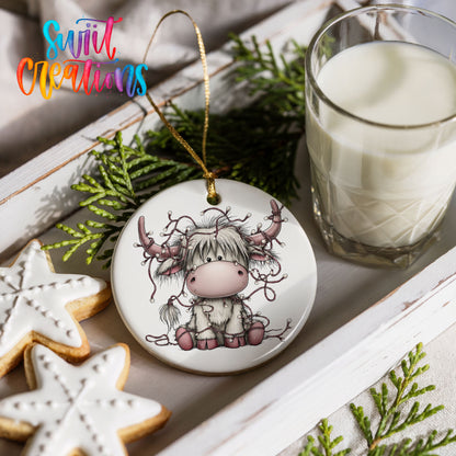 Highland cow with decorated antlers and Christmas lights ceramic Christmas ornament styled with holiday cookies and a candle