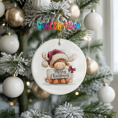 moose in a Santa hat holding a Merry Christmas sign ceramic Christmas ornament hanging on a frosted tree with ornaments