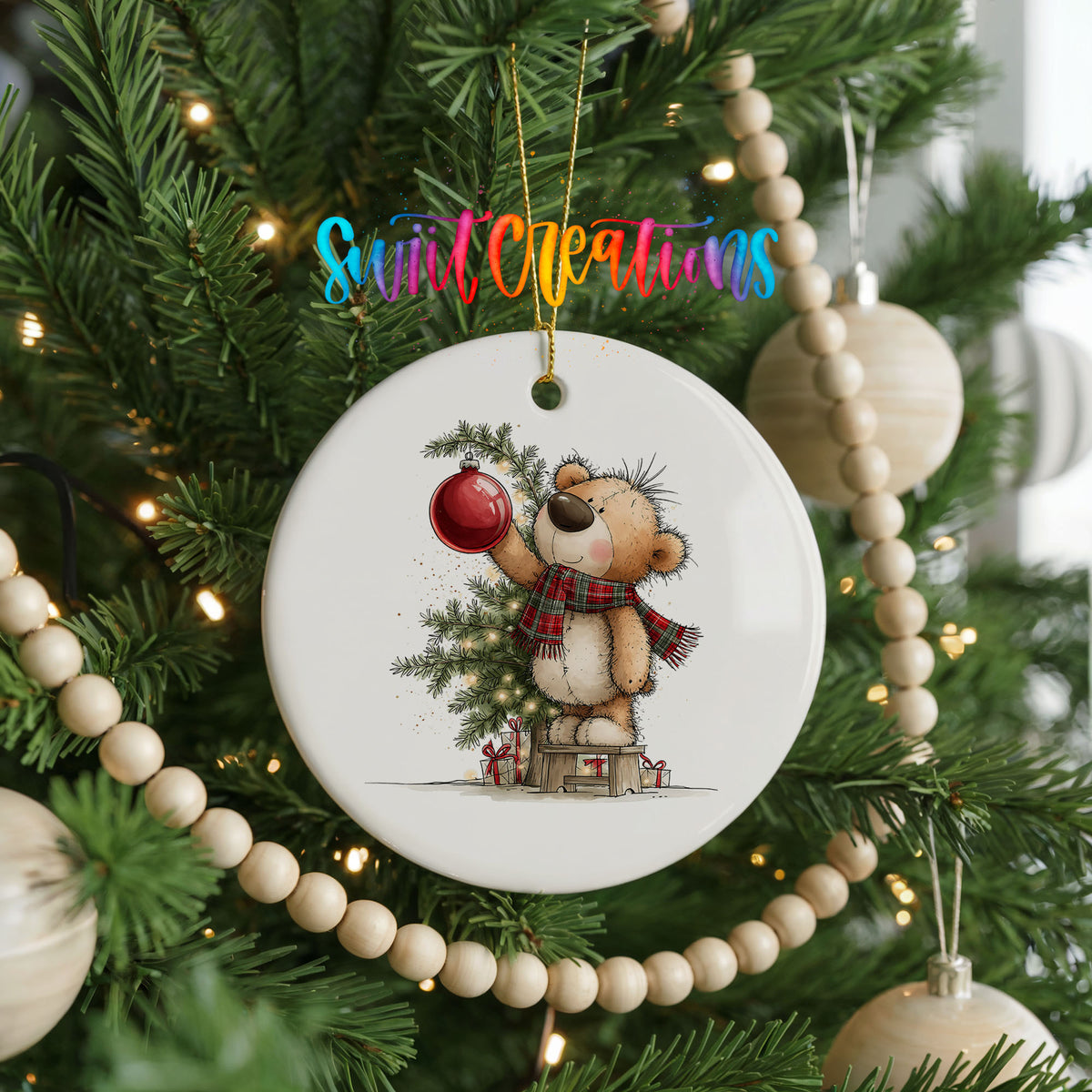teddy bear holding a red ornament beside a Christmas tree ceramic Christmas ornament hanging on a green Christmas tree
