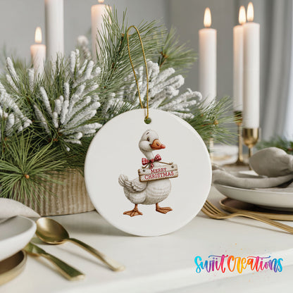 Christmas goose holding a Merry Christmas sign ceramic Christmas ornament shown in a holiday table setting