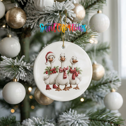 three Christmas geese wearing holiday wreaths ceramic Christmas ornament hanging on a frosted tree with ornaments