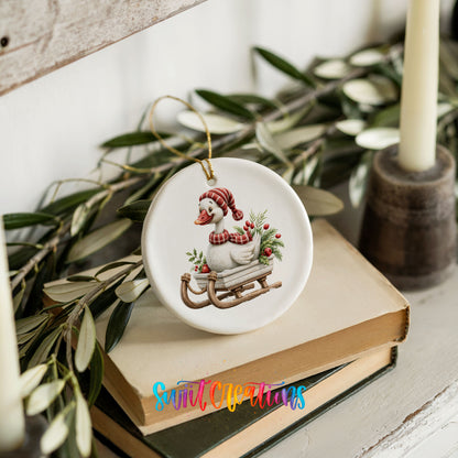 Christmas goose riding on a wooden sled ceramic Christmas ornament styled on stacked books with greenery