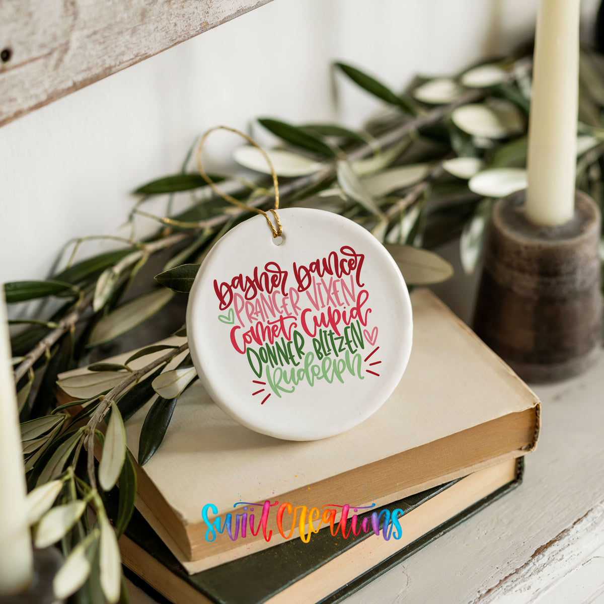 Colorful reindeer names typography ceramic Christmas ornament styled on books with holiday greenery