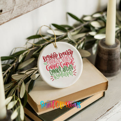 Colorful reindeer names typography ceramic Christmas ornament styled on books with holiday greenery