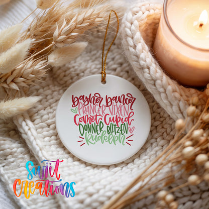 Colorful reindeer names typography ceramic Christmas ornament styled beside a candle and cozy knit blanket