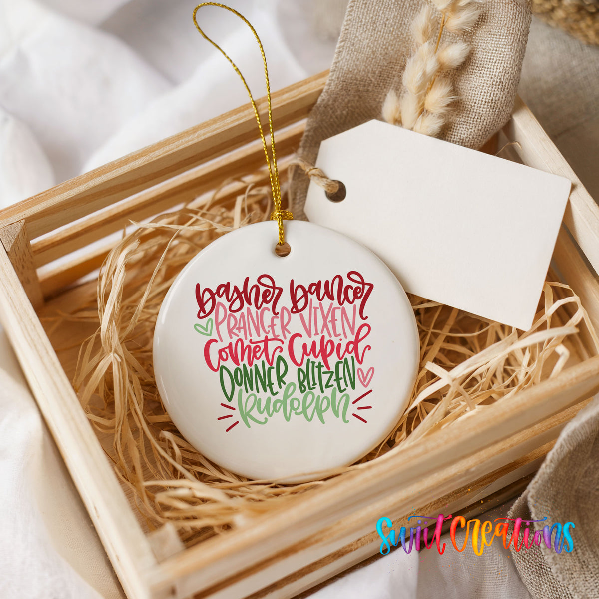 Colorful reindeer names typography ceramic Christmas ornament displayed in a rustic wooden gift crate