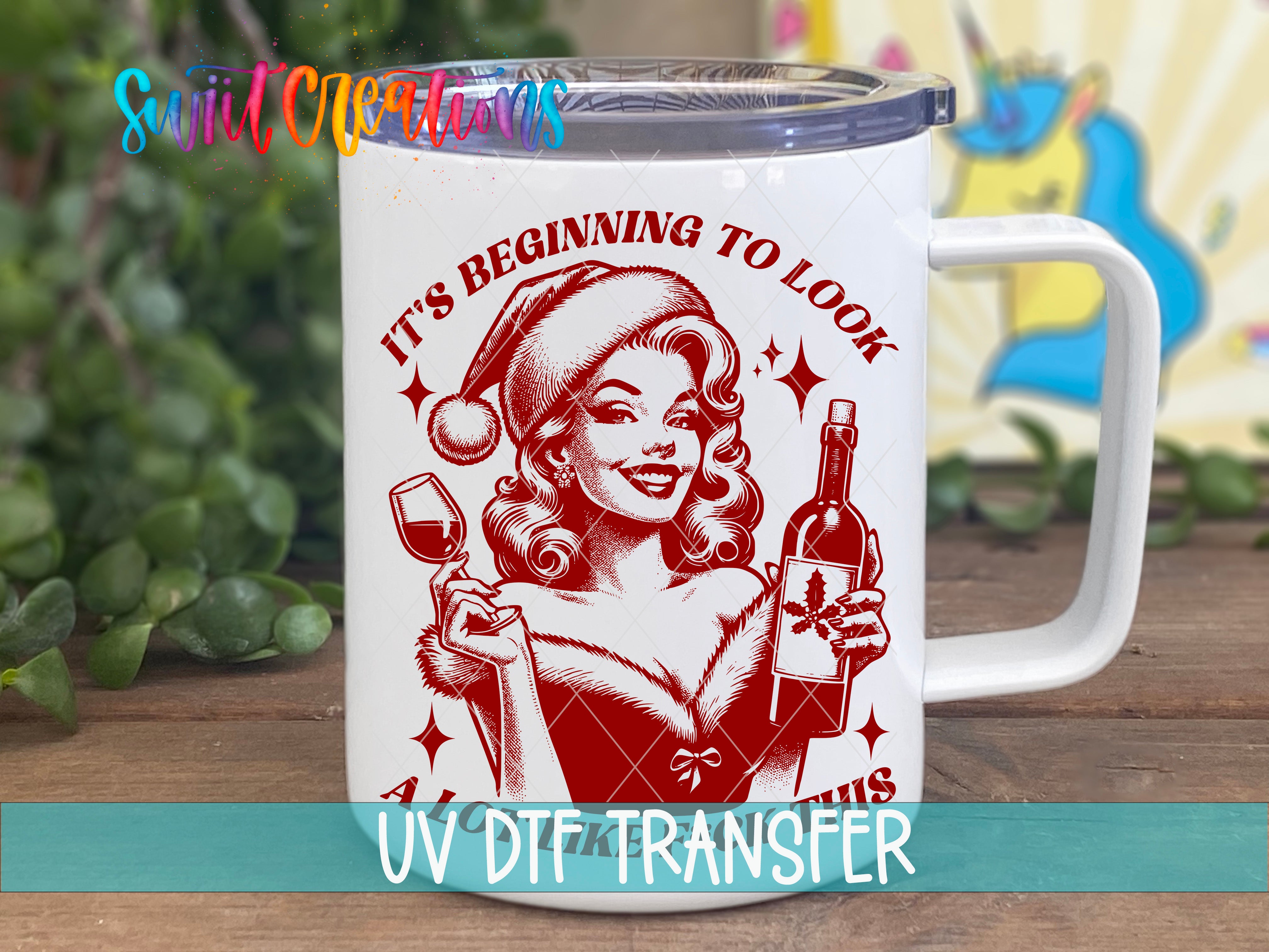 A mug with a red and white illustration of a woman wearing a Santa hat and holding a wine glass, with the text "It's Beginning to Look" and "This" below the illustration.
