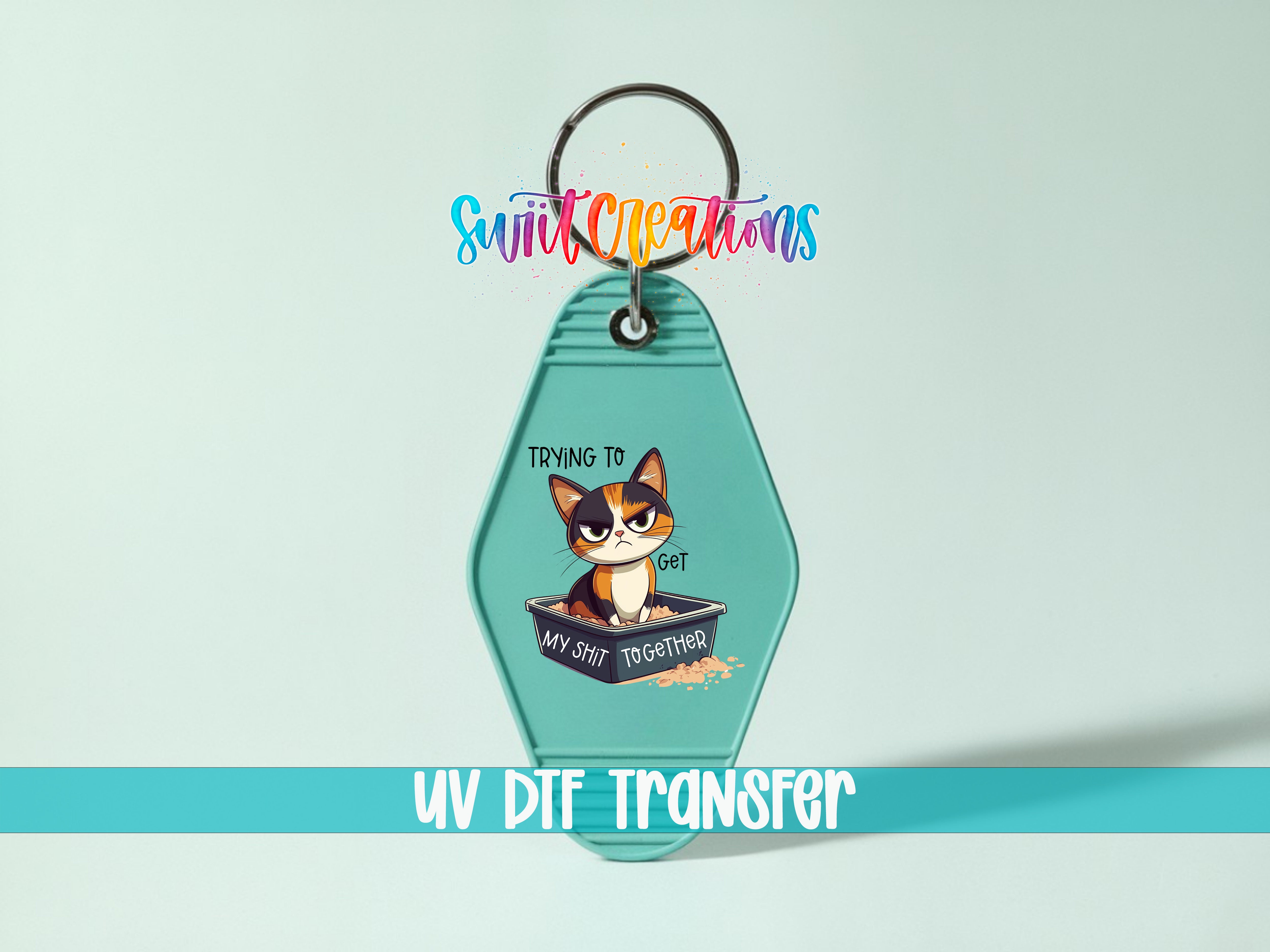 A keychain with a cartoon cat and the text "Trying to get my shit together" printed on it.