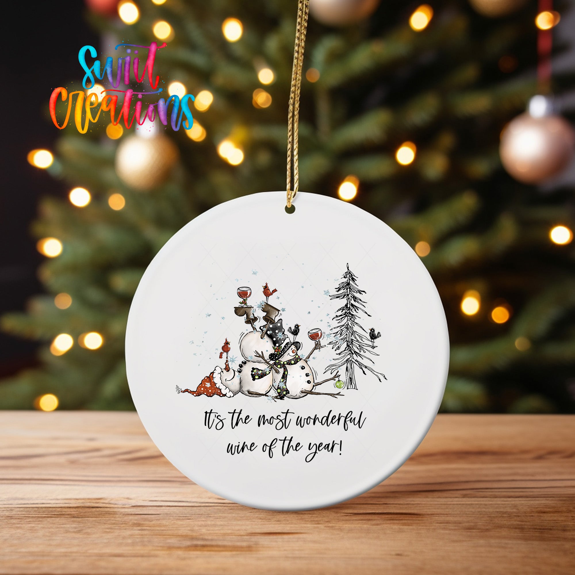 A white oval ornament with a snowman and a tree, along with the text "It's the most wonderful wine of the year!"