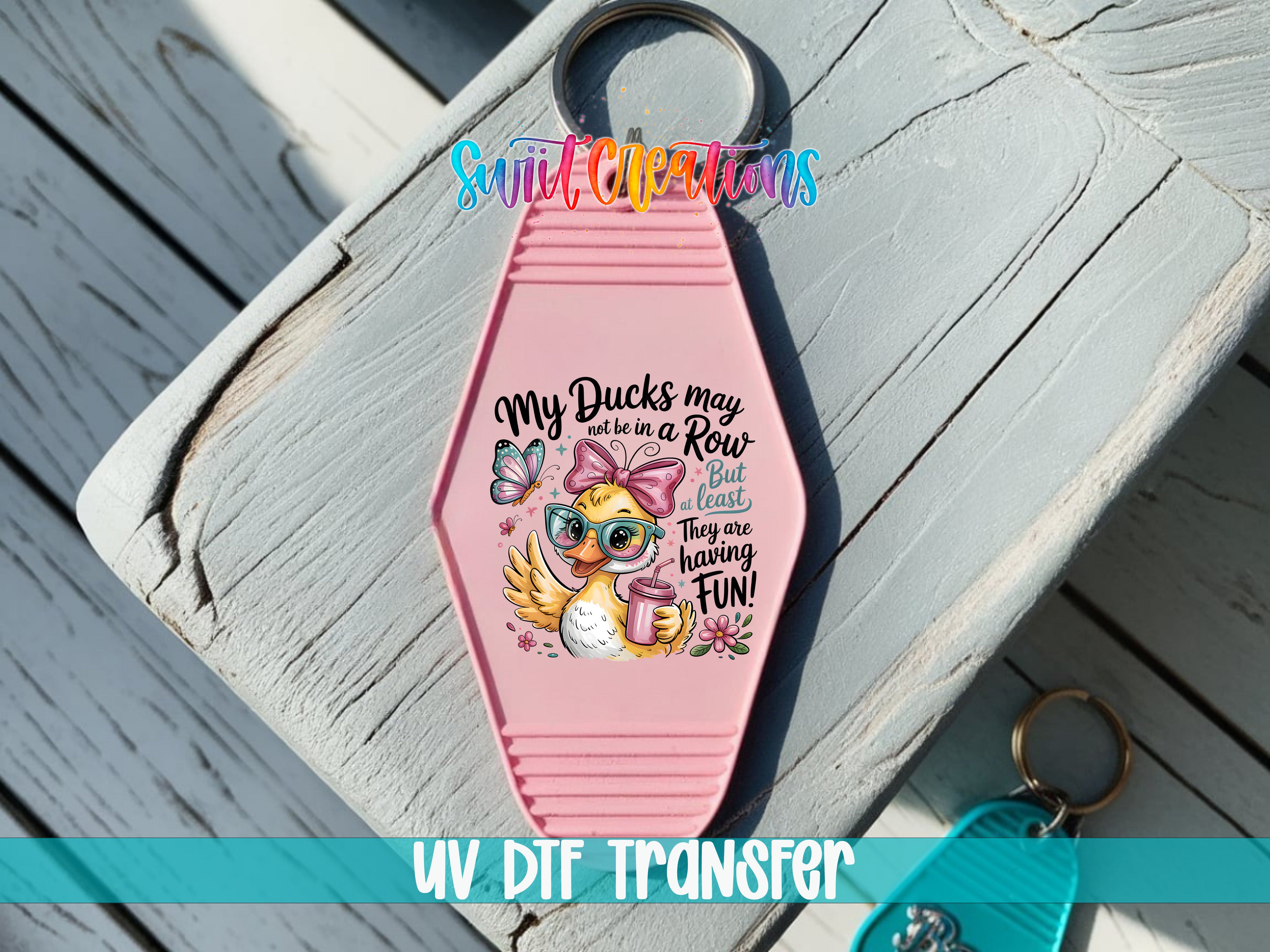 A pink keychain with a cartoon duck and sunglasses design, along with text that says "My Ducks may not be a Row but they sure are having fun".