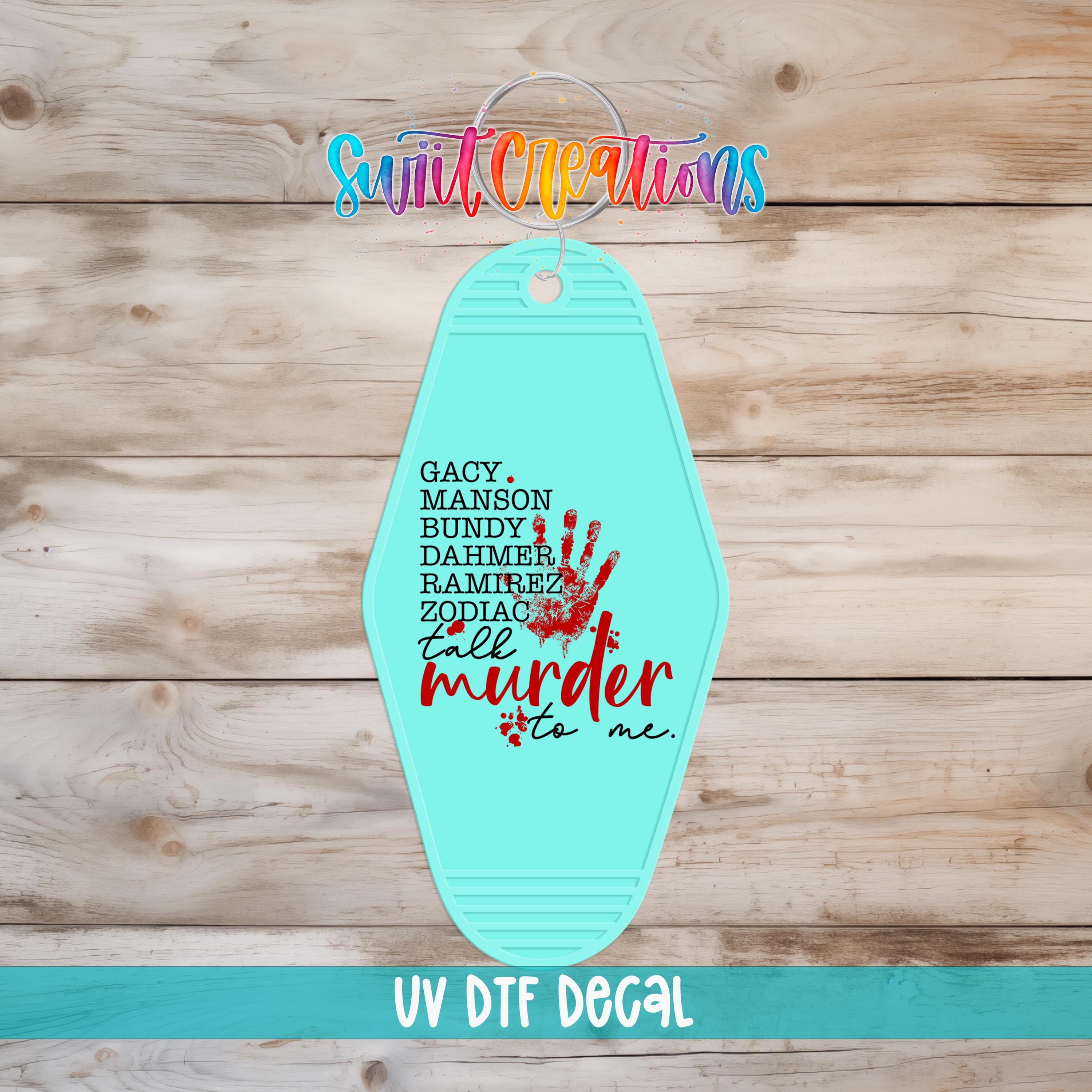 A turquoise keychain with a handprint design and text on it, placed on a wooden surface.