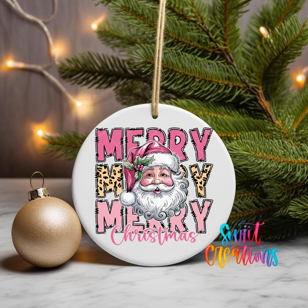 A white Christmas ornament with a Santa Claus face and the text "MERRY MARY CHRISTMAS" is displayed on a table, with a gold ornament and a pine tree in the background.