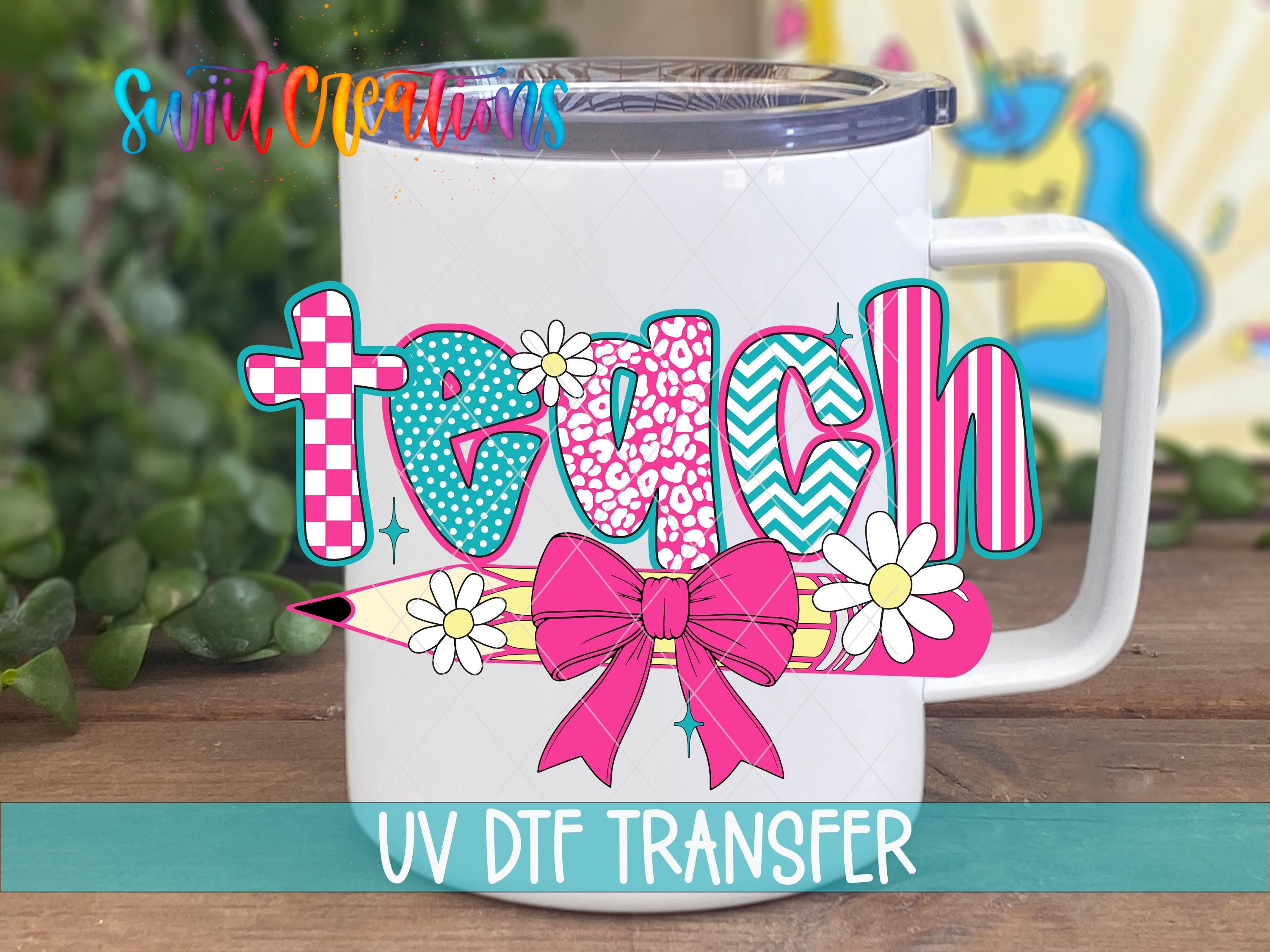 A white mug with a colorful graphic design featuring the word "Teach" and decorative elements such as flowers and a bow.