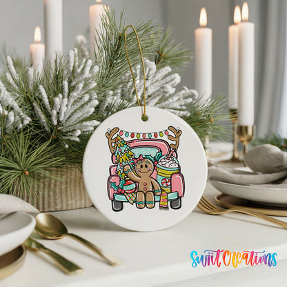 A white ceramic ornament featuring a gingerbread man riding in a pink truck, surrounded by Christmas decorations and candles.