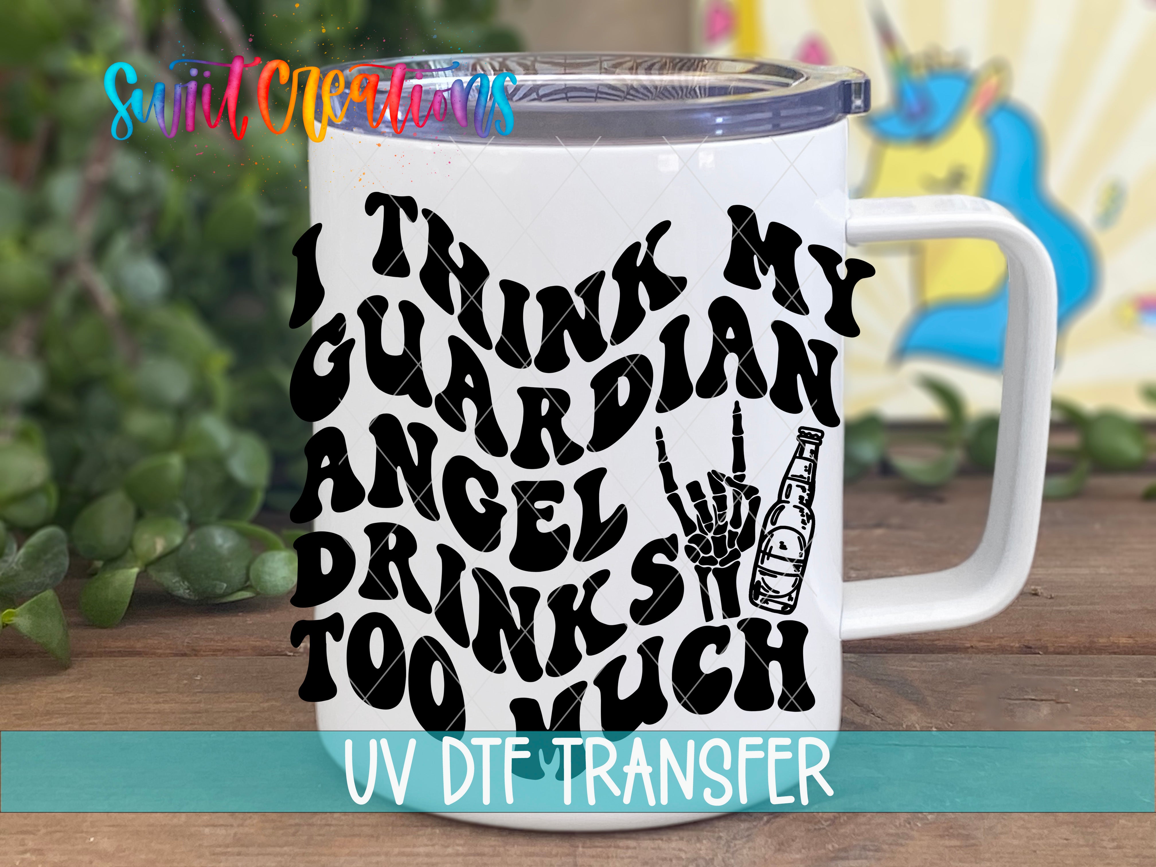 A white mug with a black text design that says "I THINK MY GUARDIAN ANGEL DRINKS TOO MUCH" along with a hand holding a beer bottle.