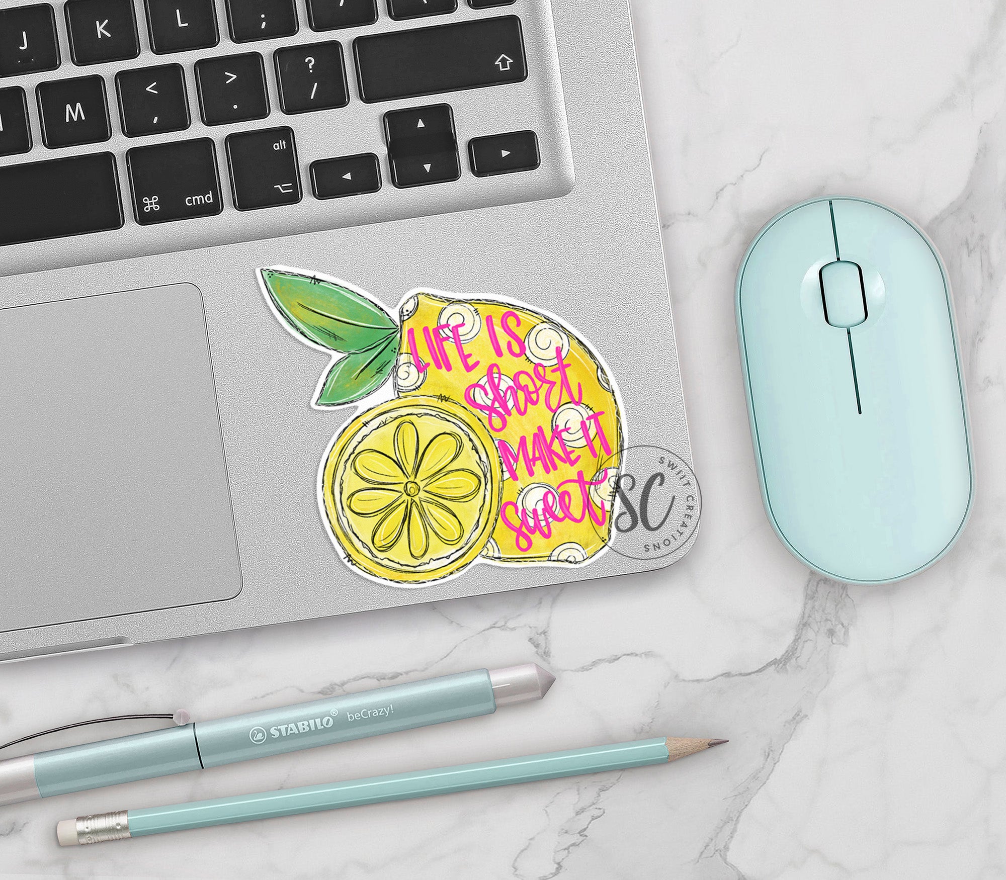 a laptop with a sticker of a lemon next to a mouse