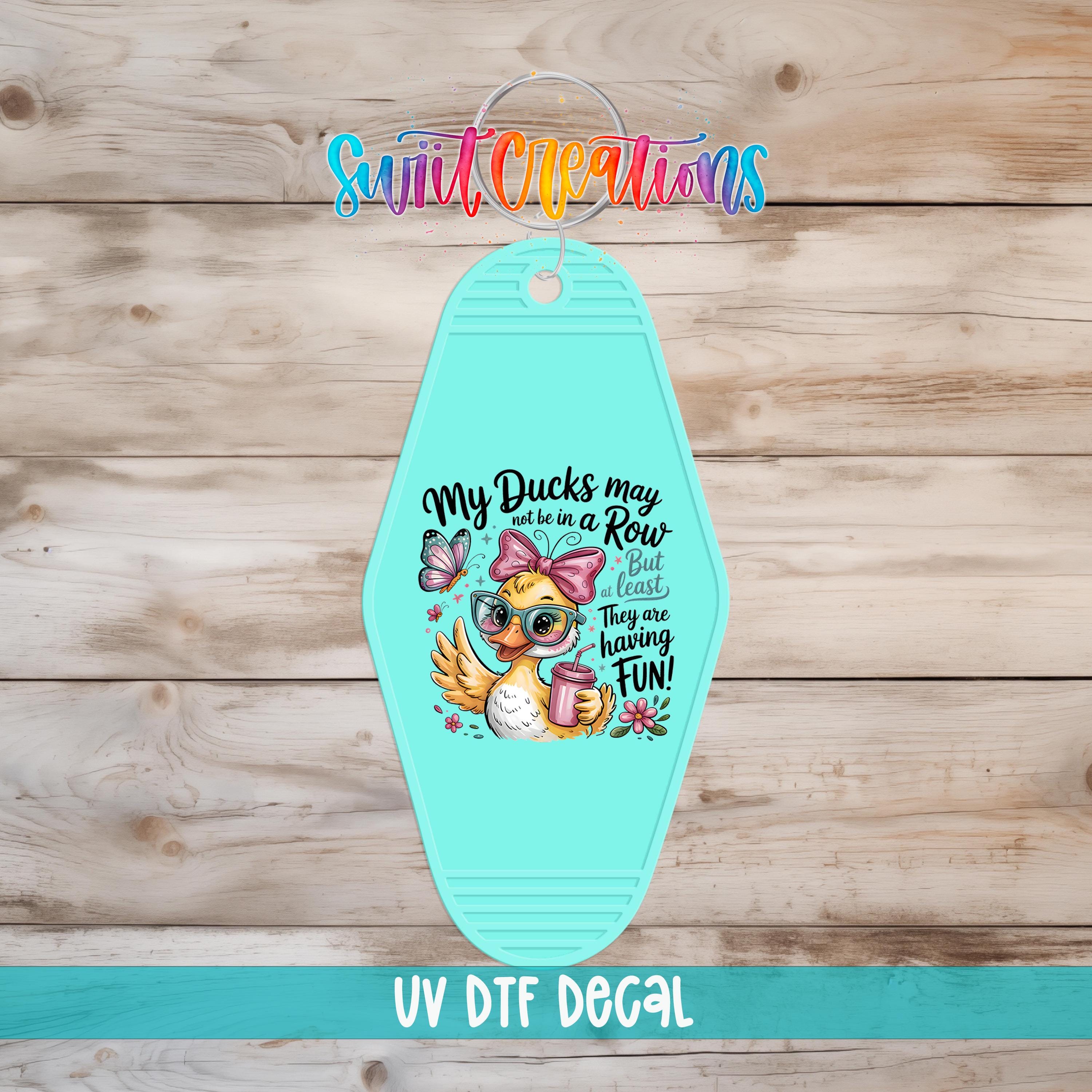 A turquoise keychain with a cartoon duck and text that says "My ducks may be in a row, but they're not having fun".