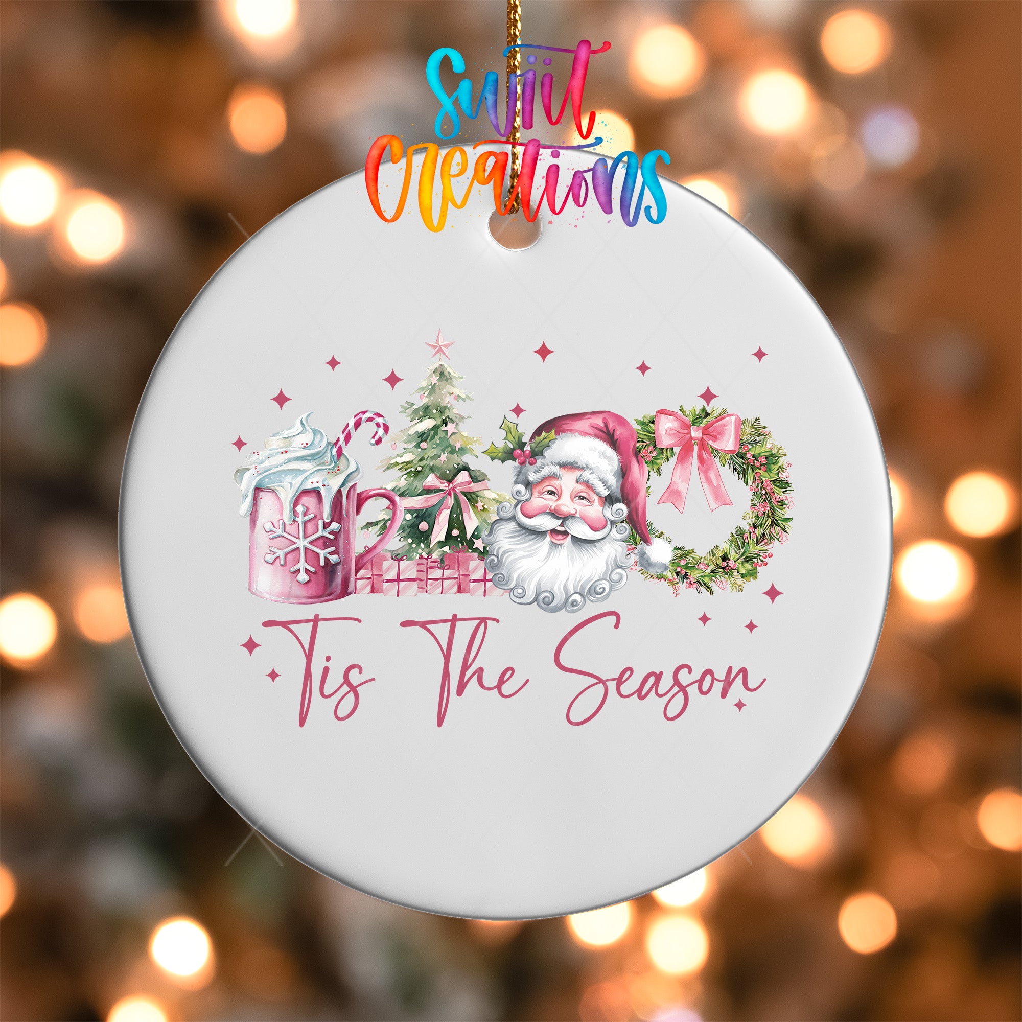 A white ornament with a Santa Claus design and the text "Tis The Season" hanging on a string.