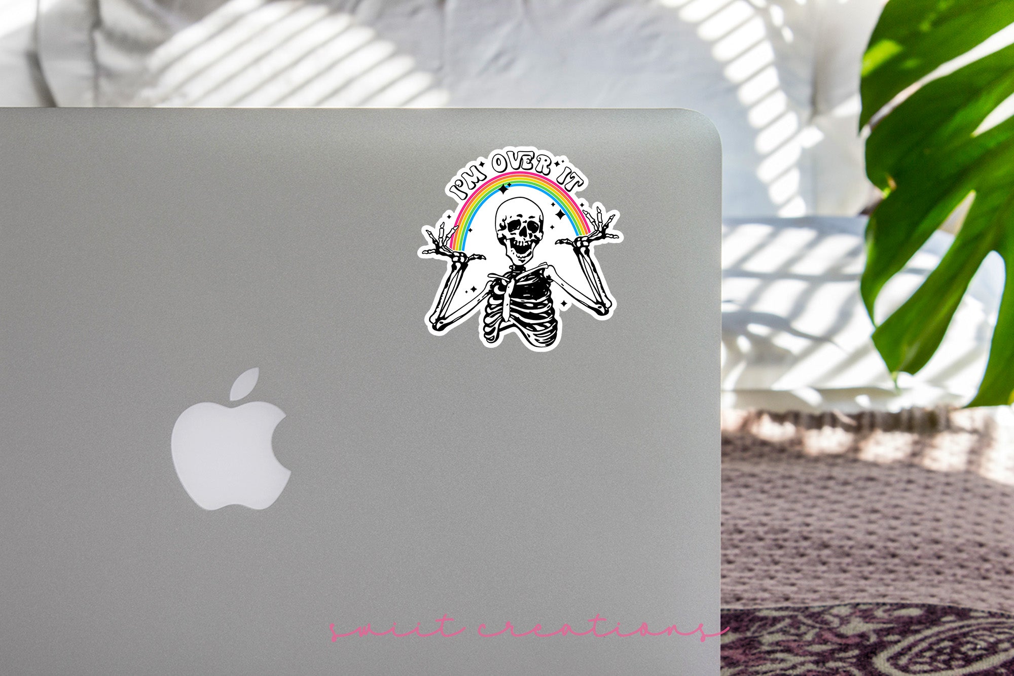 a laptop with a sticker of a skeleton holding a rainbow