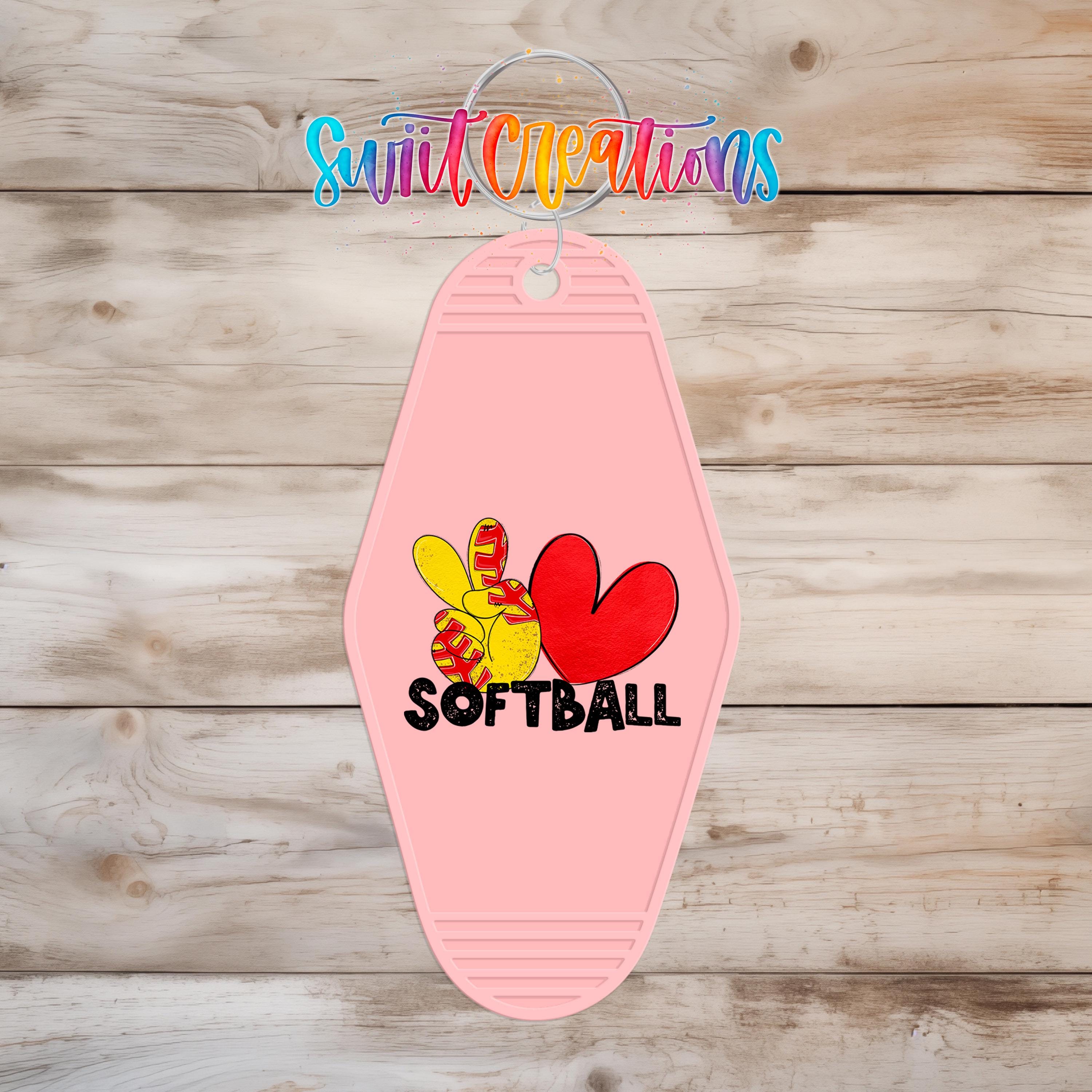 A pink keychain with a graphic design featuring a peace sign and the word "SOFTBALL".