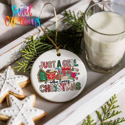 a Christmas ornament with a message that says "Just a girl who loves Christmas", surrounded by festive decorations such as cookies, a glass of milk, and greenery.