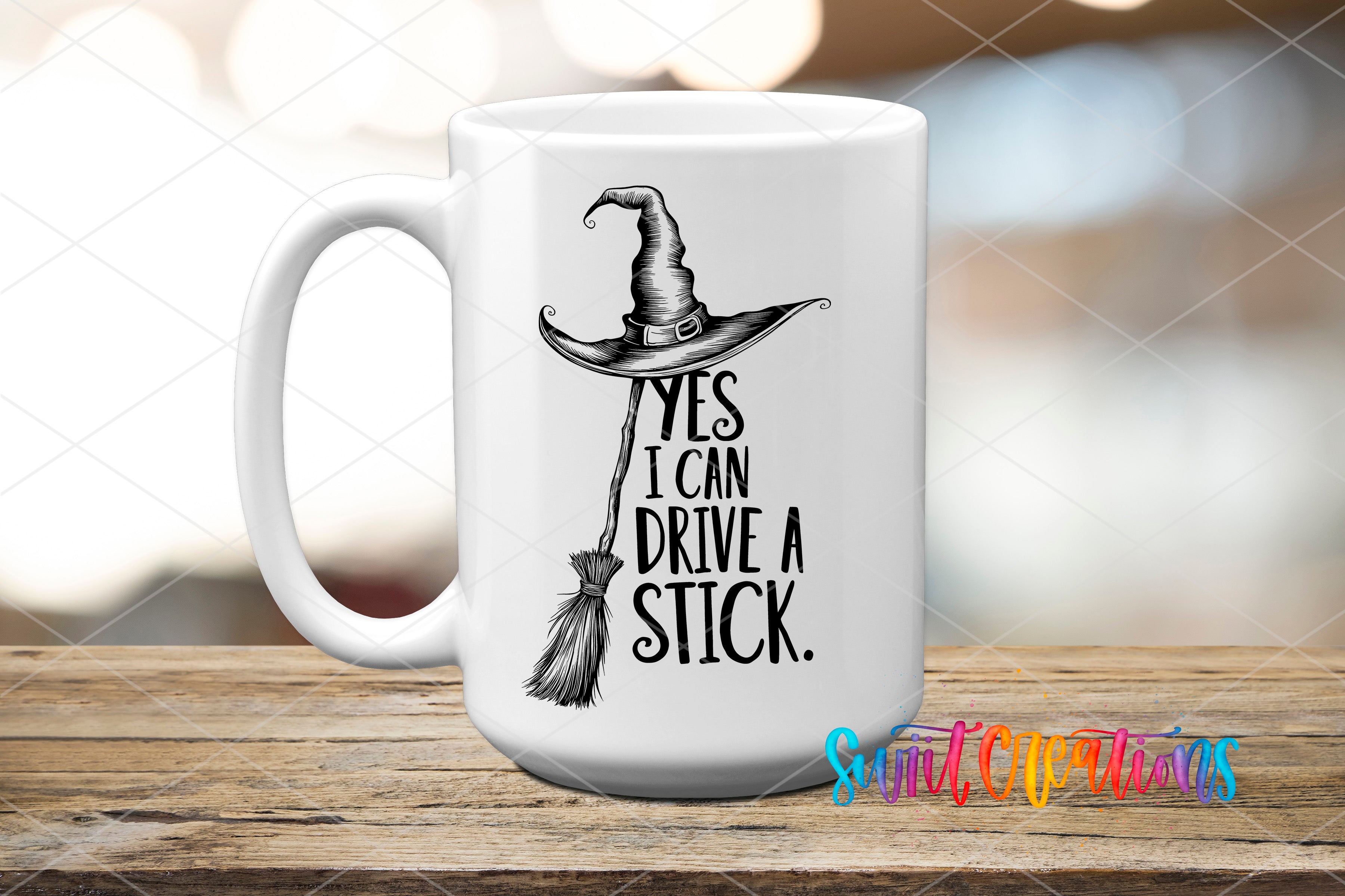 A white mug with a black illustration of a witch's hat and the text "YES I CAN DRIVE A STICK" printed on it.