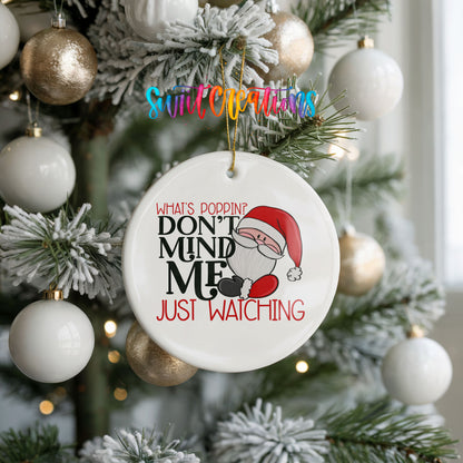 A Christmas tree decorated with ornaments, including a white ornament with a Santa Claus design and text that reads "What's Popping? Don't Mind Me Just Watching".