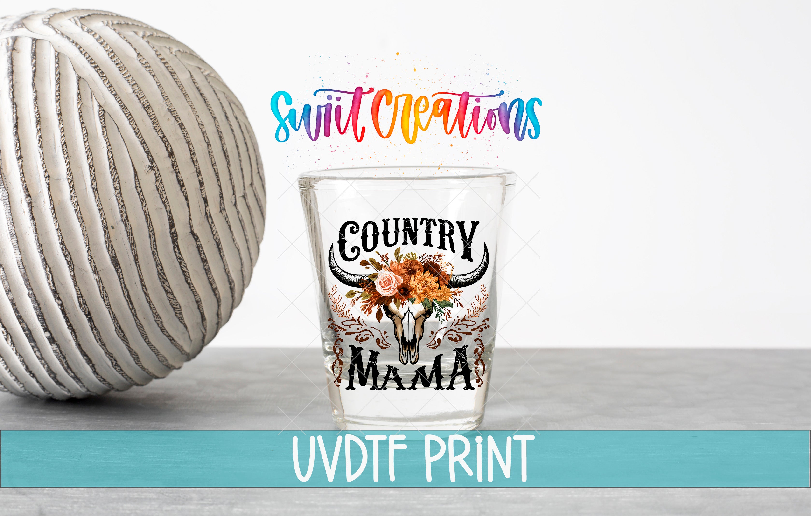 a glass with a design that says "Country Mama" and a white ball with a striped pattern next to it.