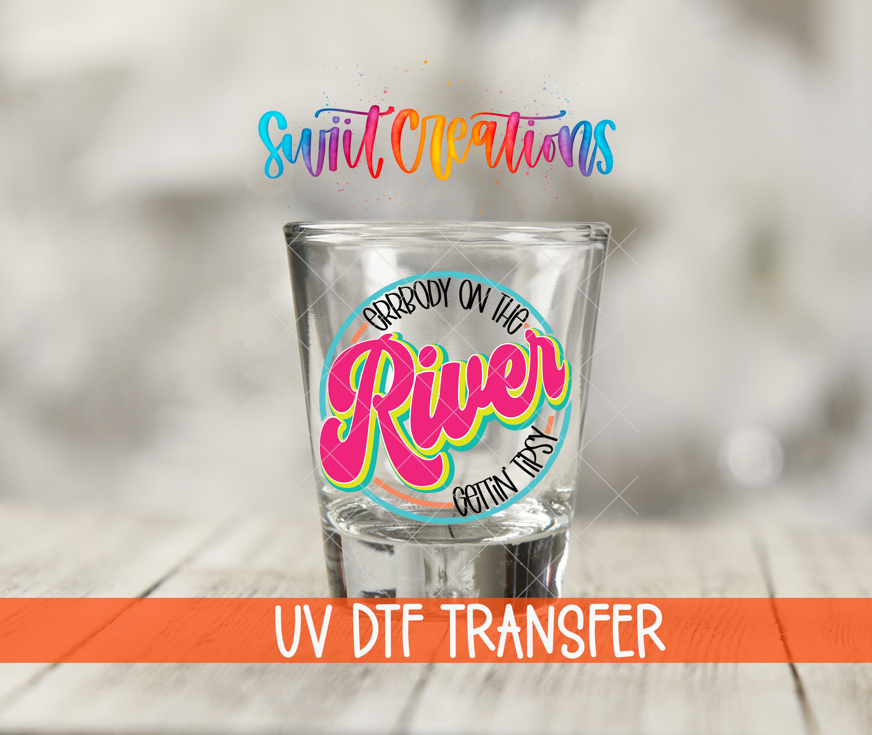 A shot glass with a colorful, stylized text design on it, placed on a wooden surface.