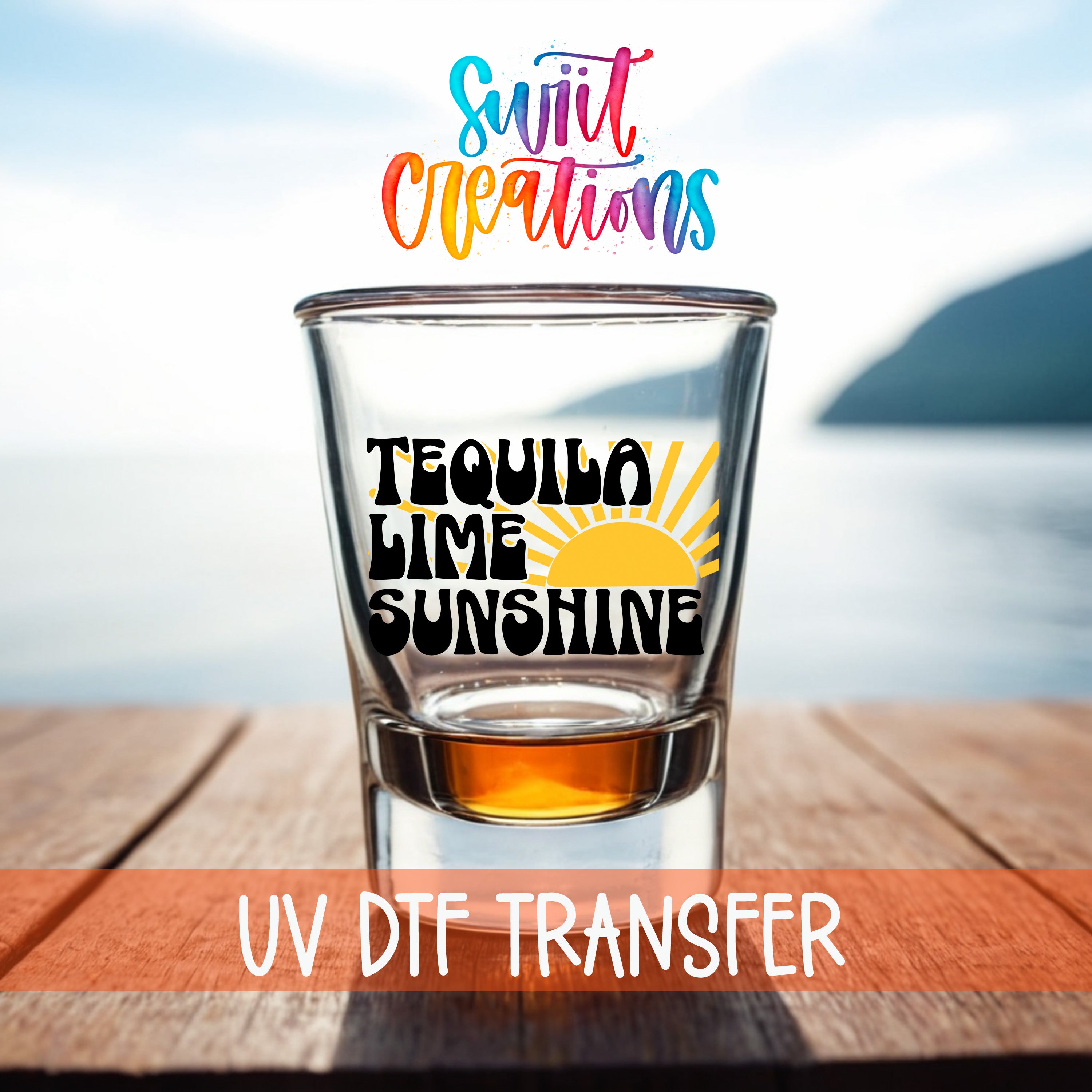 A shot glass with the text "TEQUILA LIME SUNSHINE" printed on it, placed on a wooden surface with a body of water in the background.