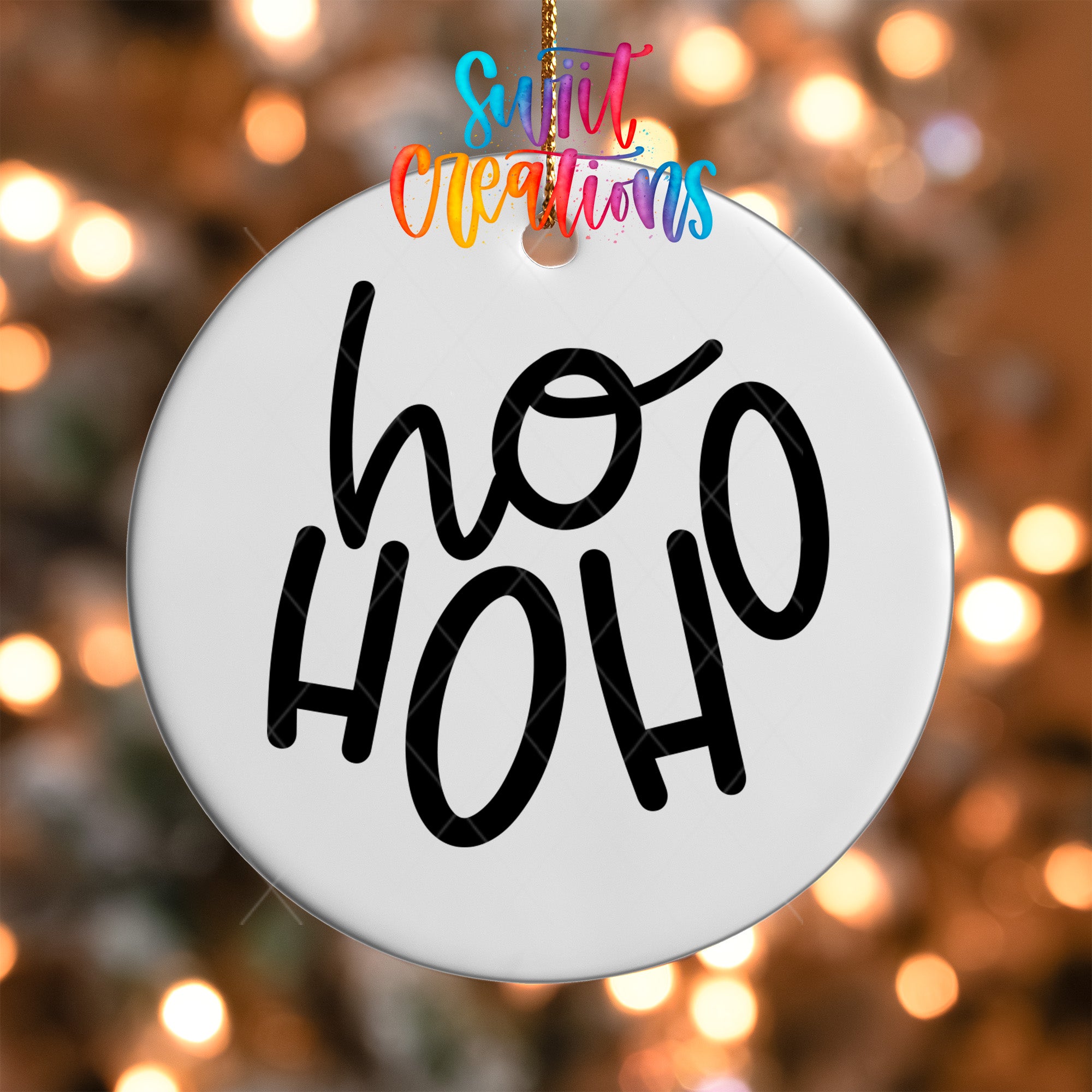 A white ornament with the text "ho ho" written on it, hanging against a background of colorful lights.