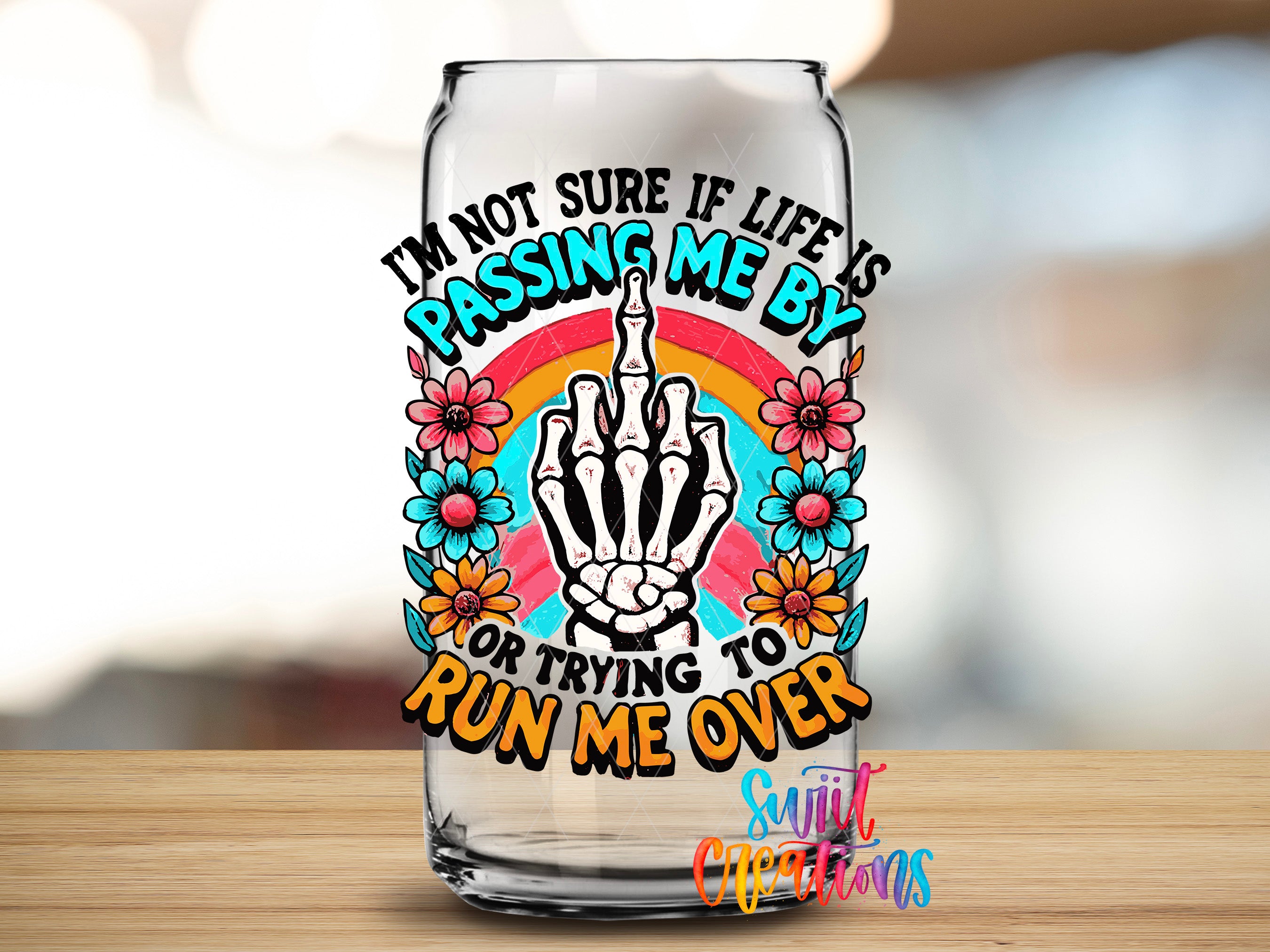 A glass can with a colorful and artistic design featuring a skeleton hand making a peace sign, surrounded by flowers and a rainbow.