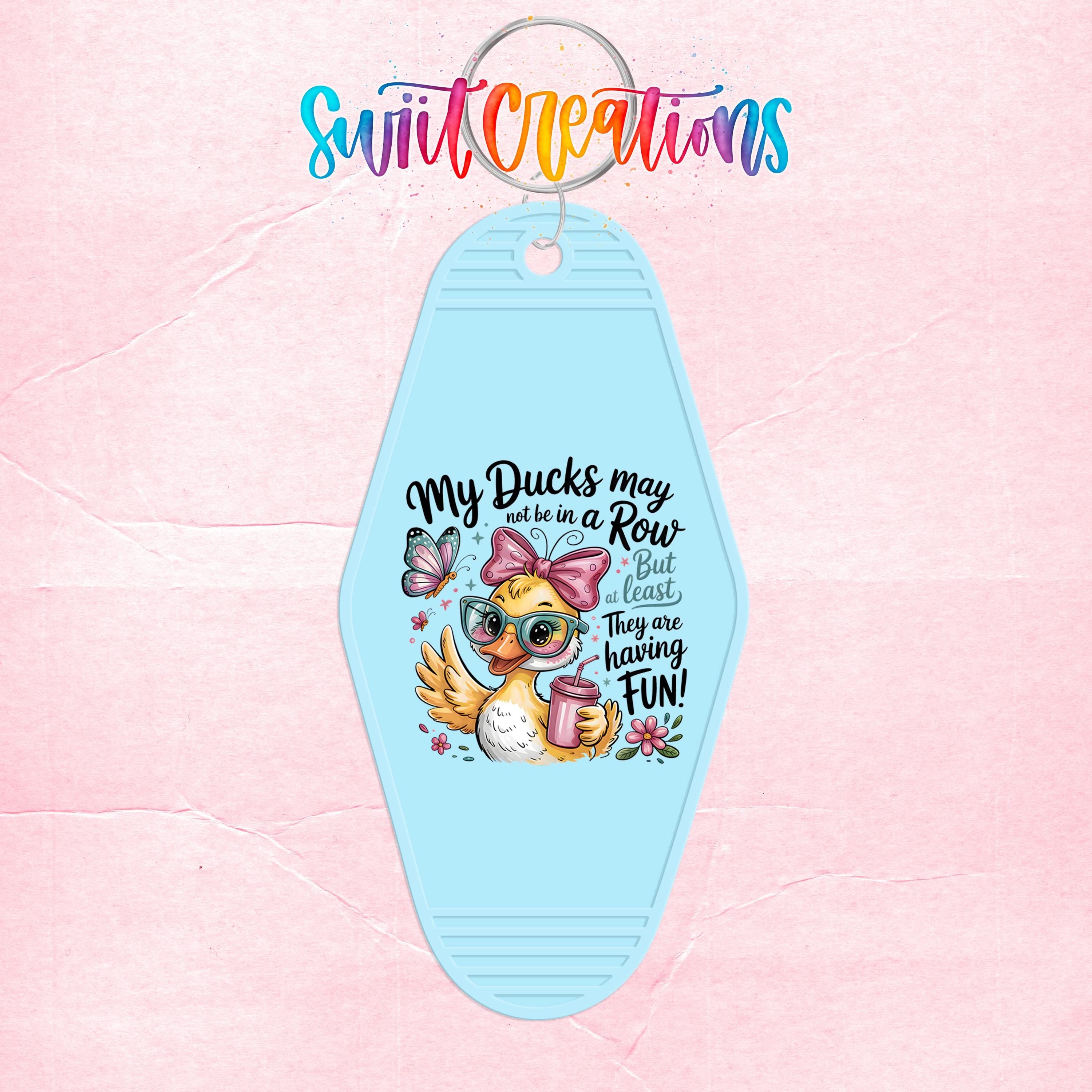 A keychain with a cartoon duck wearing sunglasses and a bow, along with text that says "My ducks may not be in a row but they are having fun!"