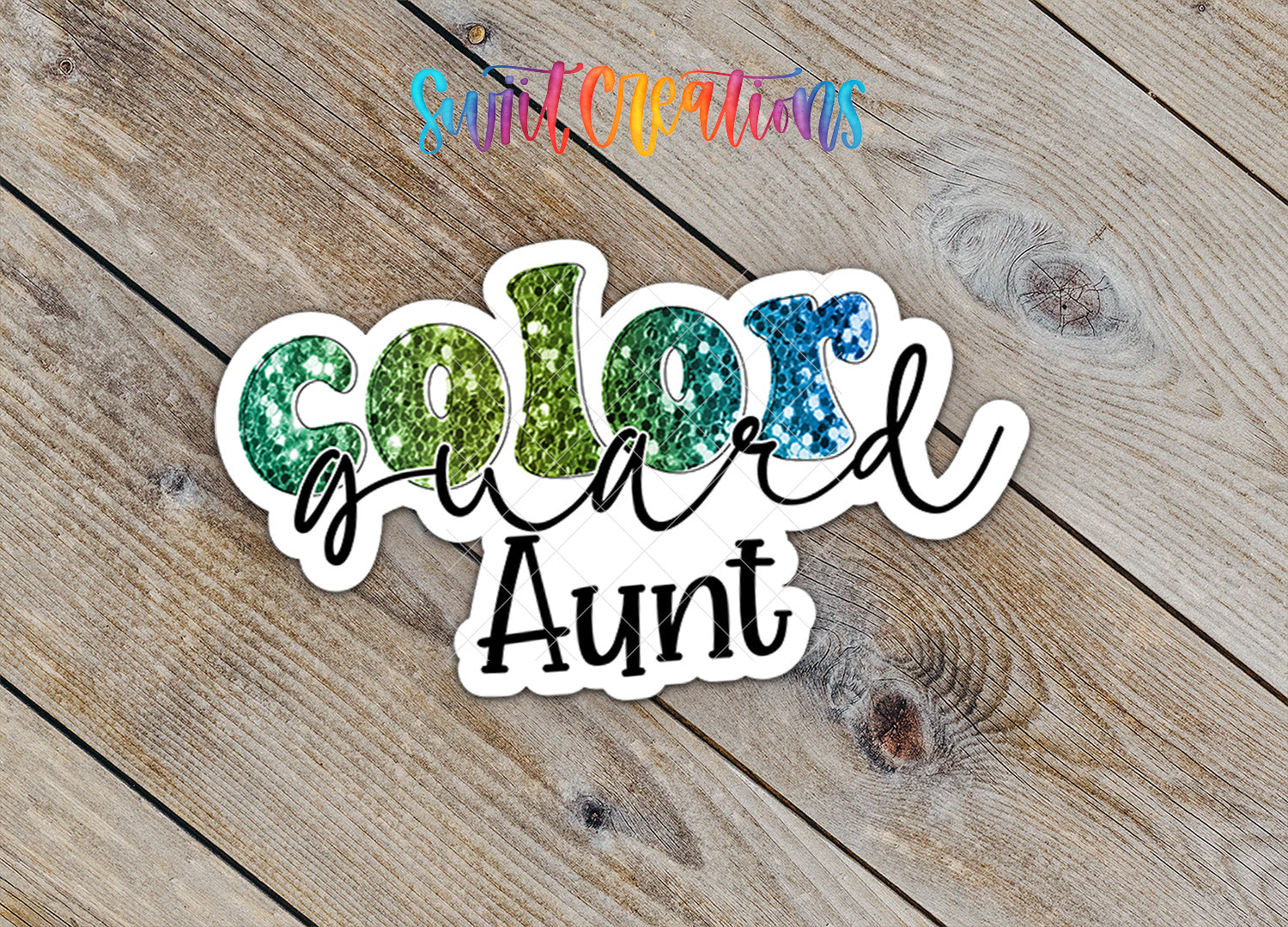 A sticker with the text "Color guard Aunt" written on it, placed on a wooden surface.