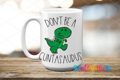 White mug displaying the Swiit Creations Don’t Be a Cuntasaurus UV DTF transfer with a funny green dinosaur.