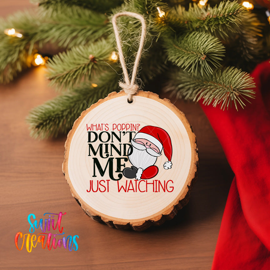 A wooden ornament with a Santa Claus image and text, hanging on a Christmas tree.