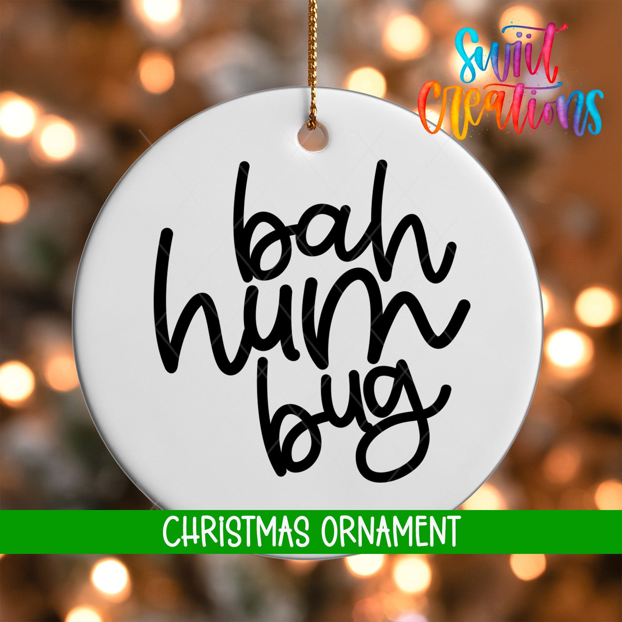 A white Christmas ornament with the text "bah hum bug" written on it, hanging against a background of colorful lights.