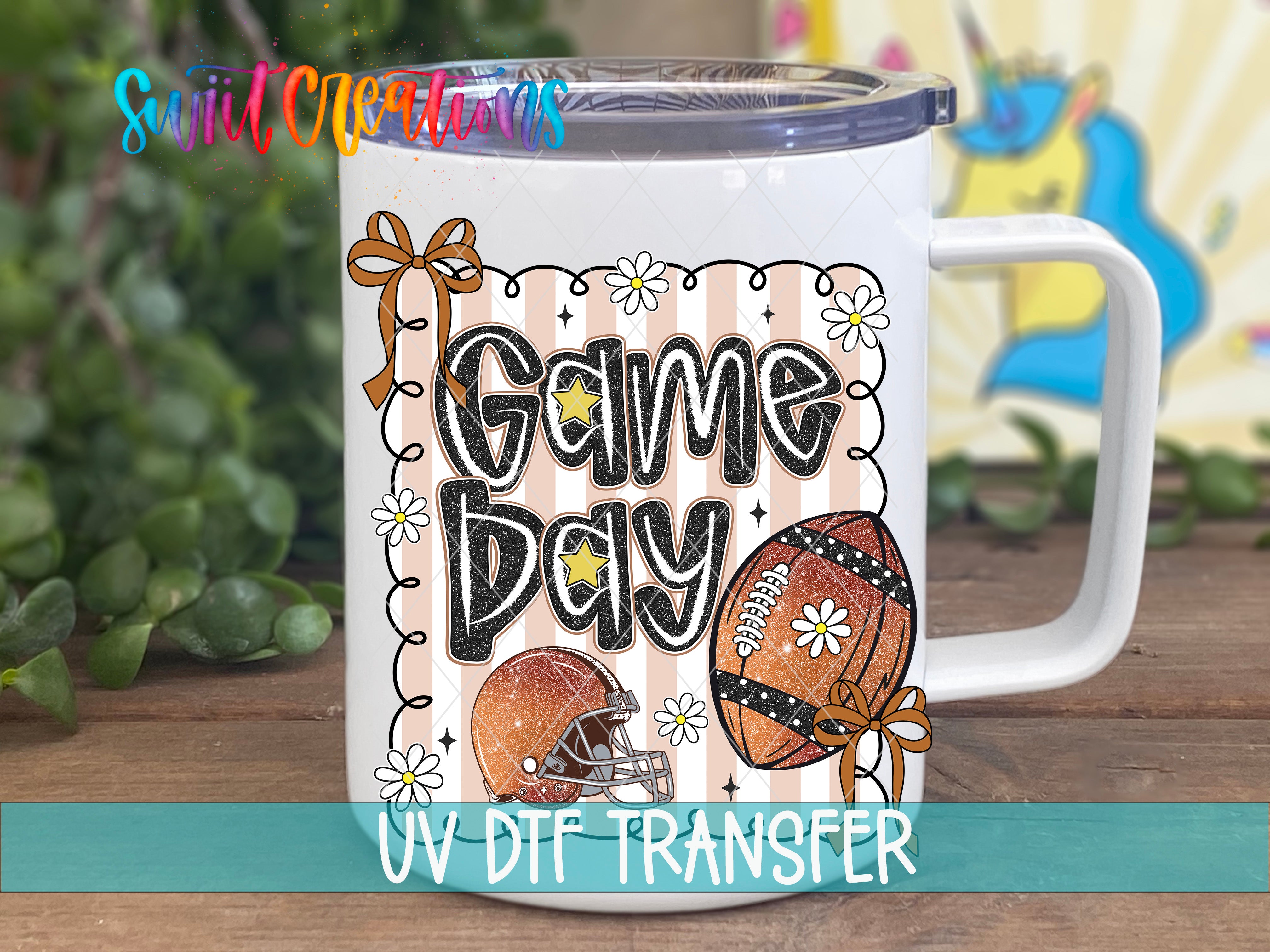 A white mug with a colorful design featuring a football, flowers, and the text "Game Day" printed on it.