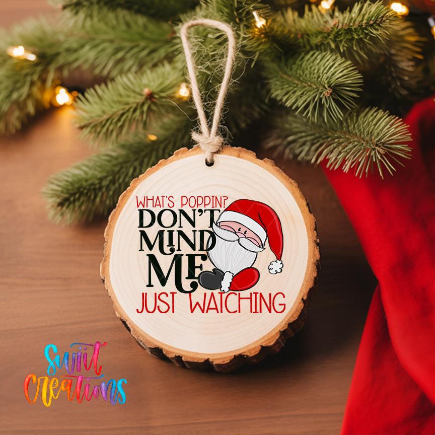 A wooden ornament with a Santa Claus image and text, hanging on a Christmas tree.